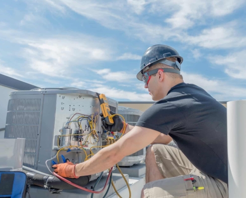 Side view of an HVAC technician at work fixing a unit